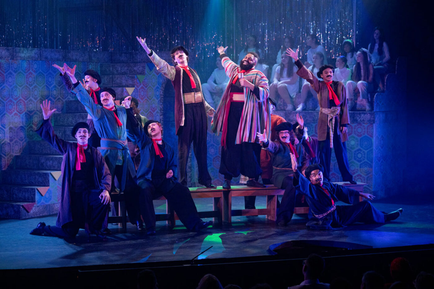 Joseph: ensemble dance, arms raised under purple lights