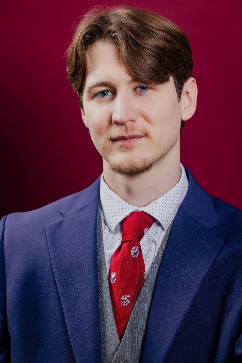 Anthony Edward, headshot — blue suit on red background